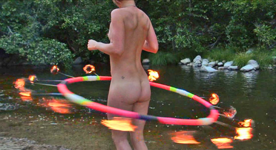 flaming hoola hoop spins around a nude performer