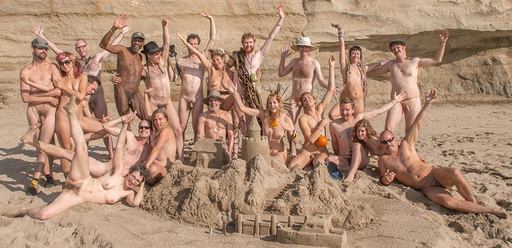 naked club group at the beach in california with a giant sand castle